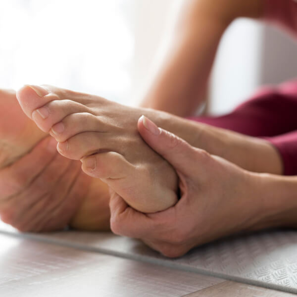 Une femme tient son pied sur un tapis de yoga, en position d'étirement ou de méditation.