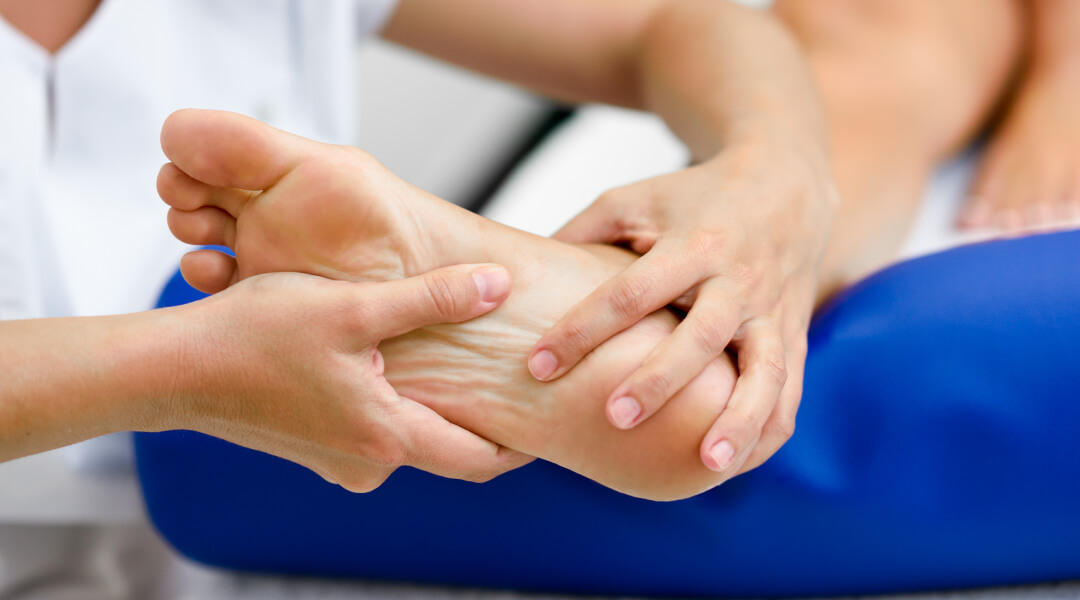 Une personne recevant un massage des pieds, détendue sur une chaise avec les yeux fermés.