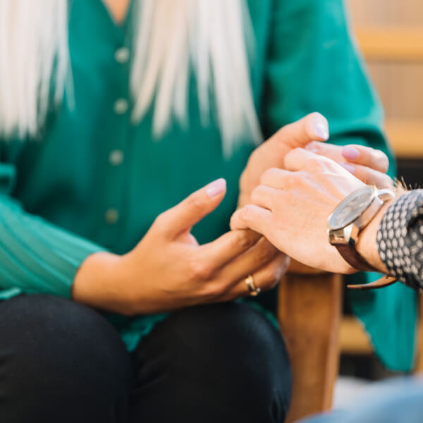 Une femme tient la main d'une autre femme, symbolisant le soutien et la connexion entre elles.